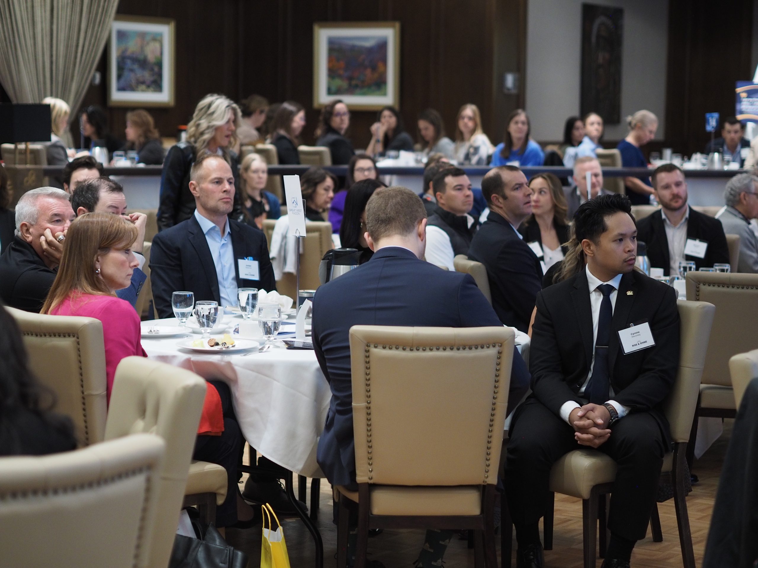 Guests seated around breakfast tables listen to the program at Rise & Shine 2026 at the Calgary Petroleum Club.